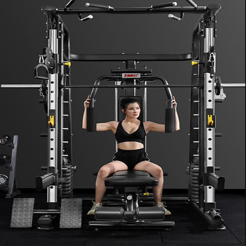 A person in athletic wear sits on a bench using a multi-function gym machine. The background is dark, highlighting the equipment. They are performing an upper body exercise, gripping handles with both hands.
