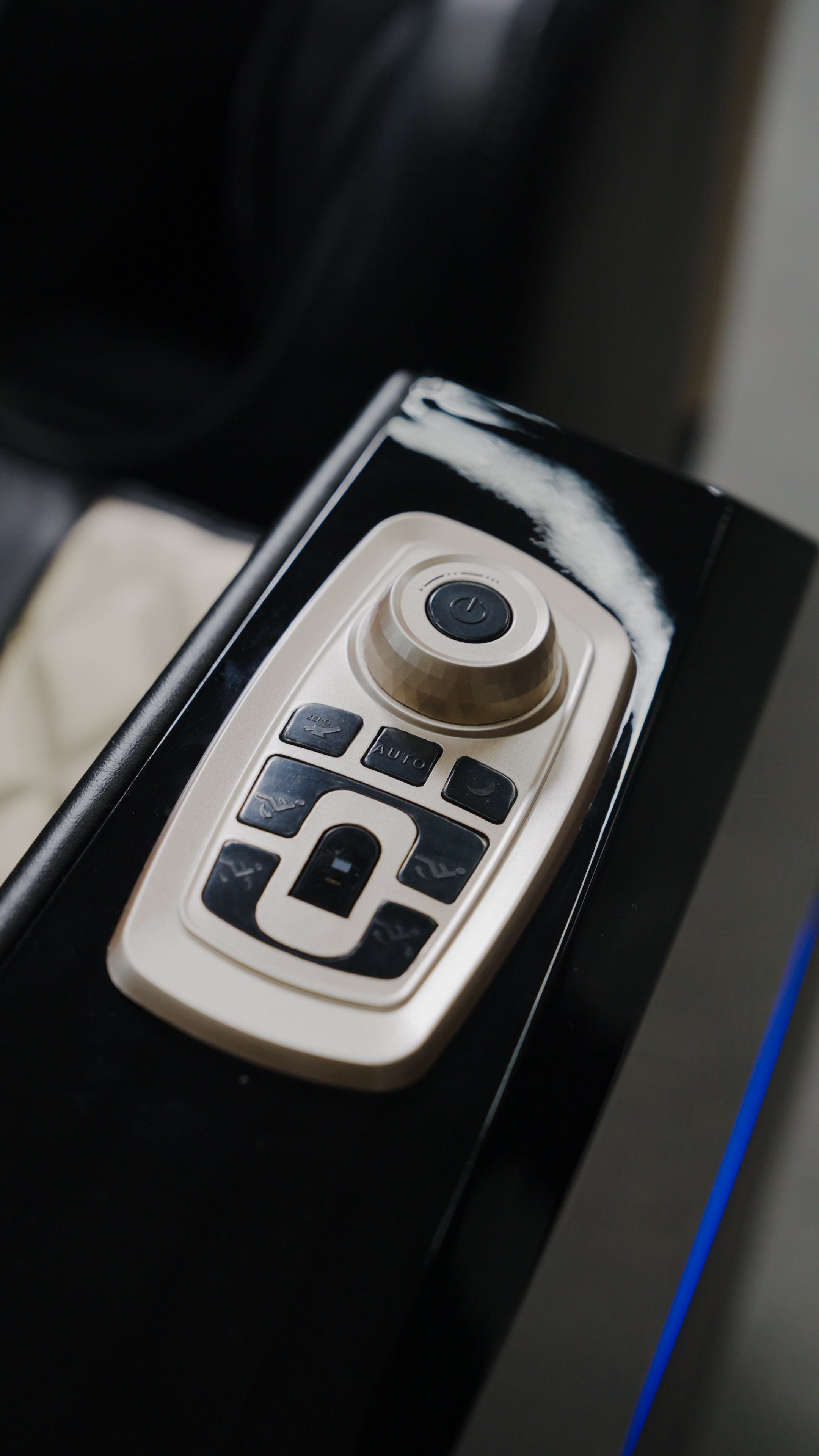 Close-up of the BefitNow Canada 4D SL Luxury Voice Control Custom Massage Chair's control panel, featuring black buttons and a round dial on a sleek black surface.