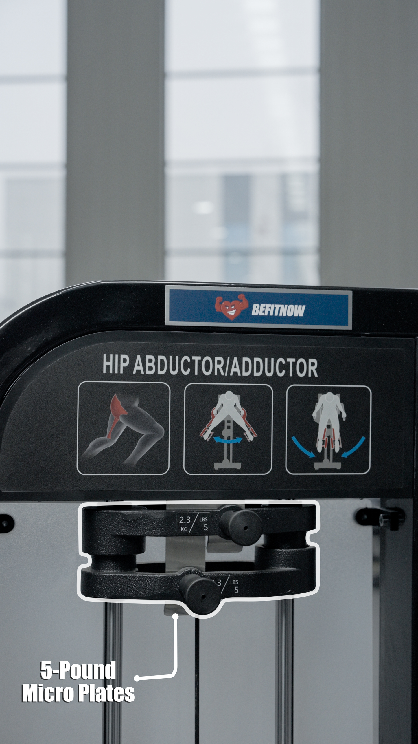 The BefitNow Canada HS32 Abductor/Adductor gym machine has illustrated instructions, two labeled knobs for 2.3 kg/5 lb micro plate adjustments, and is positioned near large windows that fill the space with diffuse light.