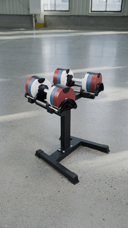 Two BefitNow Canada 80lbs Adjustable Cast Iron Dumbbells, featuring red, white, and blue weight plates, rest on a sleek black metal stand set atop a smooth light gray concrete floor in a spacious, well-lit room—an ideal choice for anyone seeking to upgrade their home gym with stylish and space-saving dumbbells.