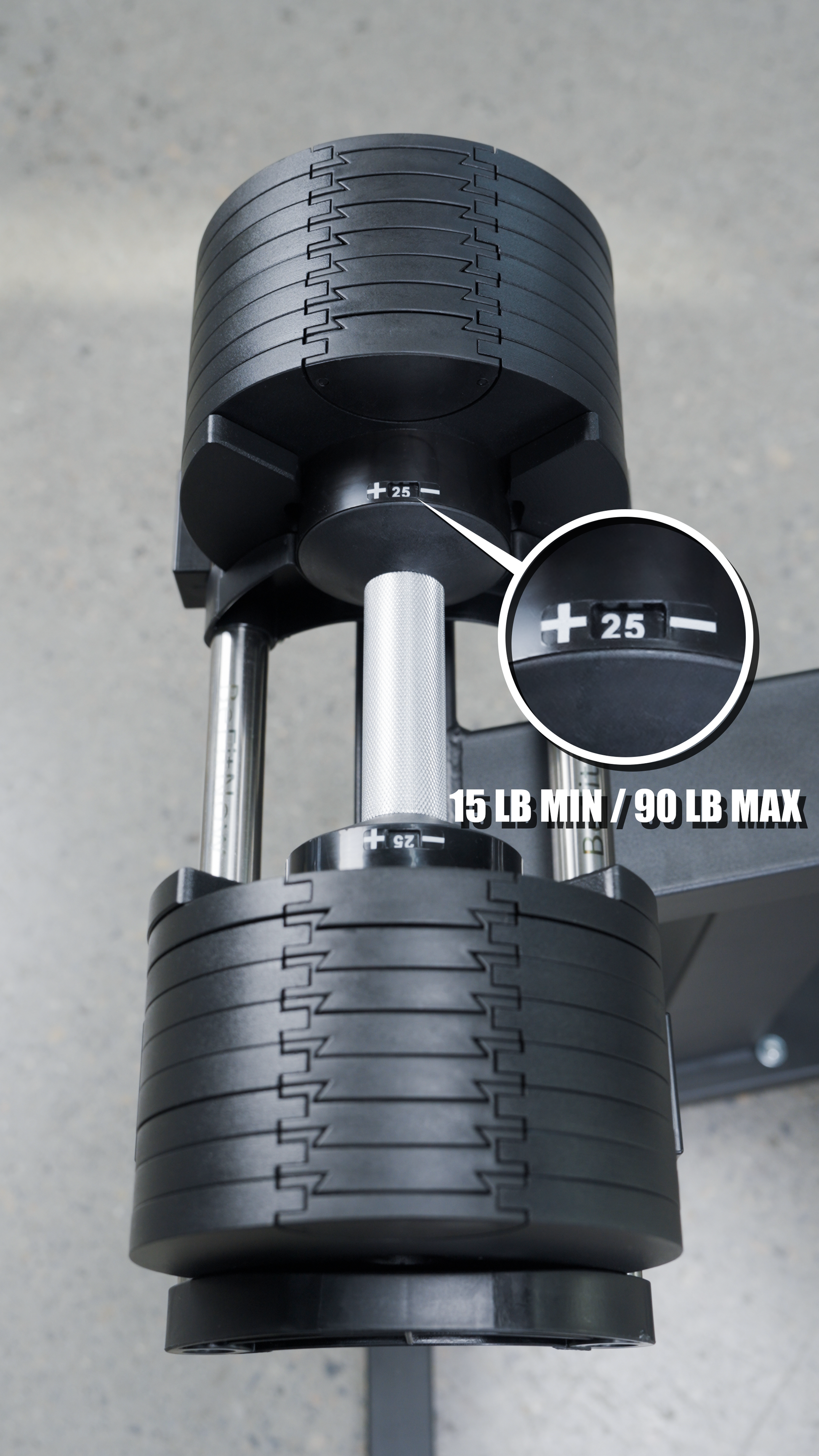 Close-up of the BefitNow Canada 90lbs Adjustable Cast Iron Dumbbell Pair—perfect for home gyms—with a dial set to 25 lbs and text “15 LB MIN / 90 LB MAX.” The black dumbbell with silver handle rests on a gray surface.