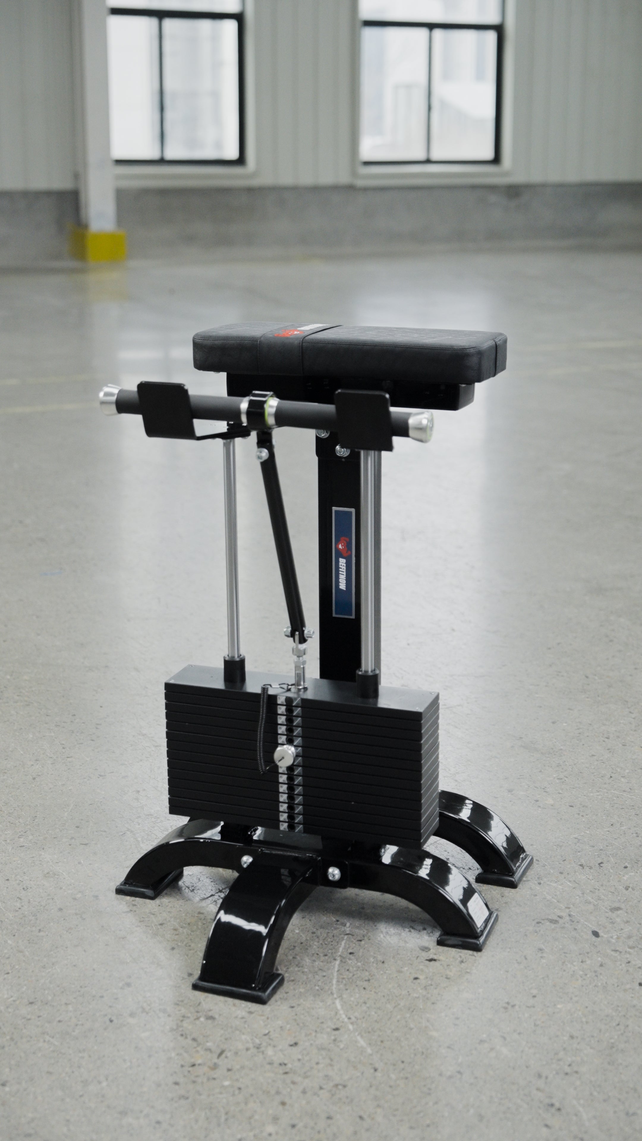 The BefitNow Canada Forearm Trainer is a black, rectangular padded machine with metal bars and a sturdy base, ideal for any modern gym space. This affordable equipment stands out in bright, industrial-style rooms with large windows.