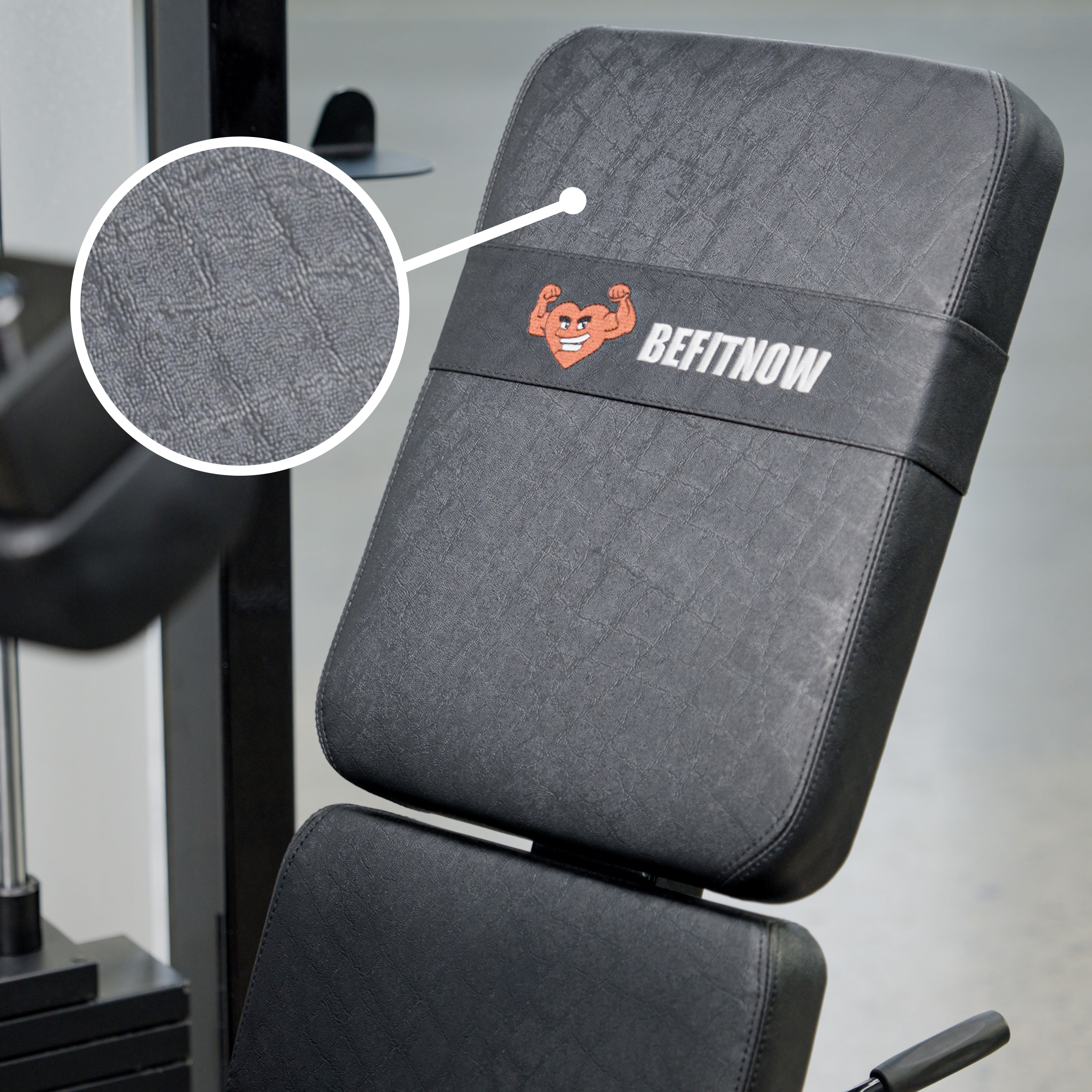 Close-up of BefitNow Canada’s Dual Function Leg Extension Leg Curl Machine in black; a flexing arm logo is embroidered on the backrest, with an inset showing the textured fabric pattern in detail.