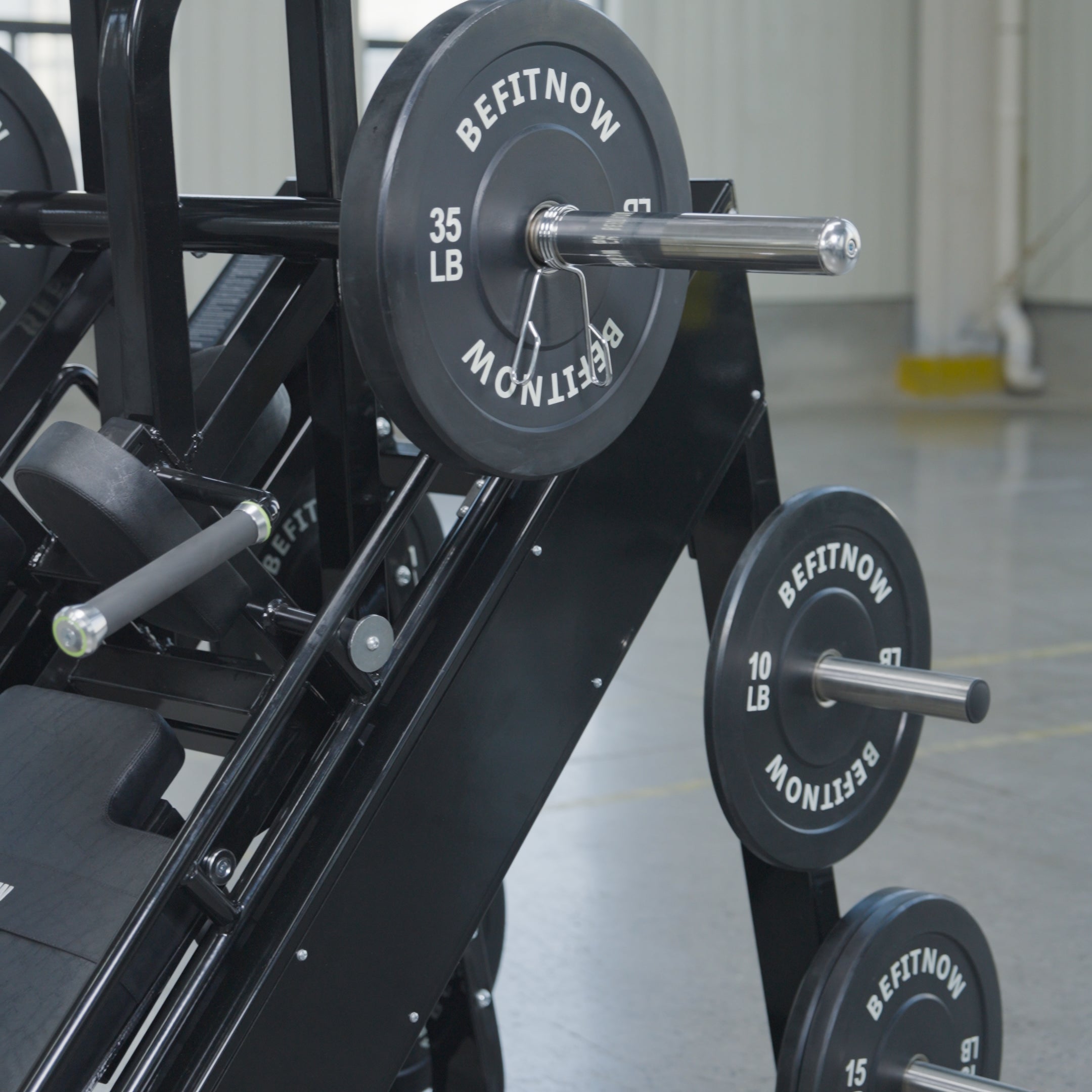 The 45 Degree Leg Press Hack Squat by BefitNow Canada sits on a concrete floor with white walls, loaded with black BEFITNOW weight plates (35 lb and 10 lb), totaling 560 lbs. Its dimensions are 93" x 65" x 57".