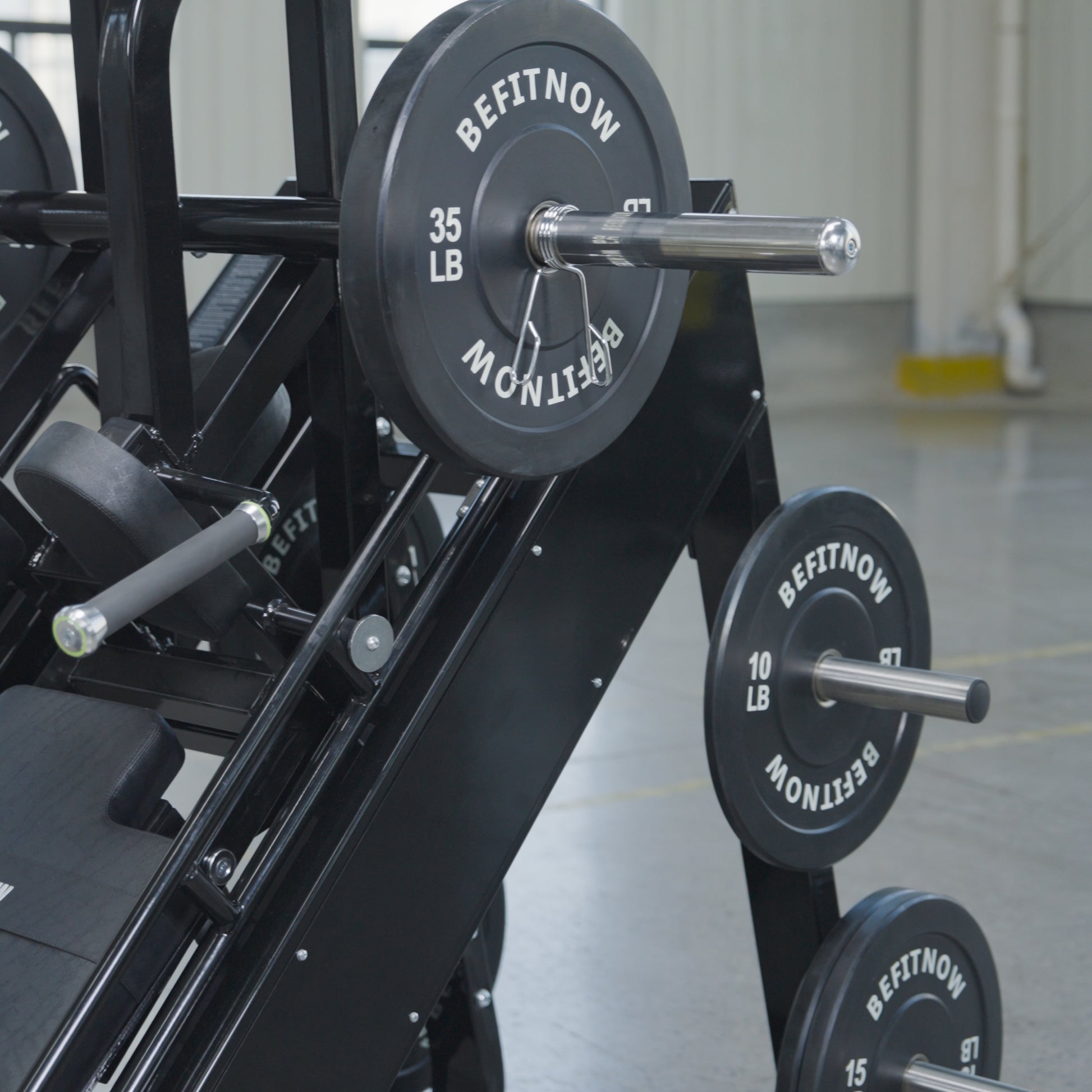 The 45 Degree Leg Press Hack Squat by BefitNow Canada sits on a concrete floor with white walls, loaded with black BEFITNOW weight plates (35 lb and 10 lb), totaling 560 lbs. Its dimensions are 93" x 65" x 57".