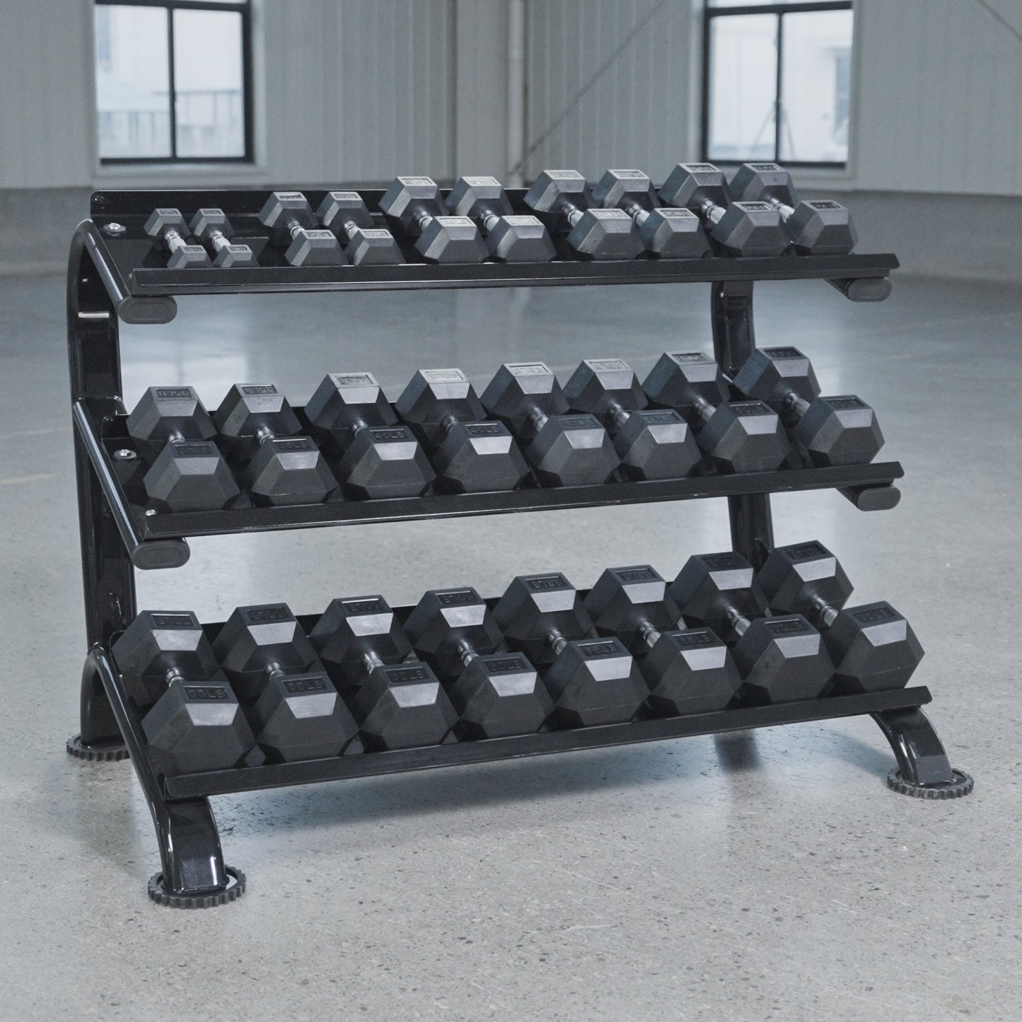 The BefitNow Canada 3 Tier Commercial Hex Dumbbell Rack displays black hex dumbbells on a smooth concrete floor in a spacious, well-lit gym with large windows.