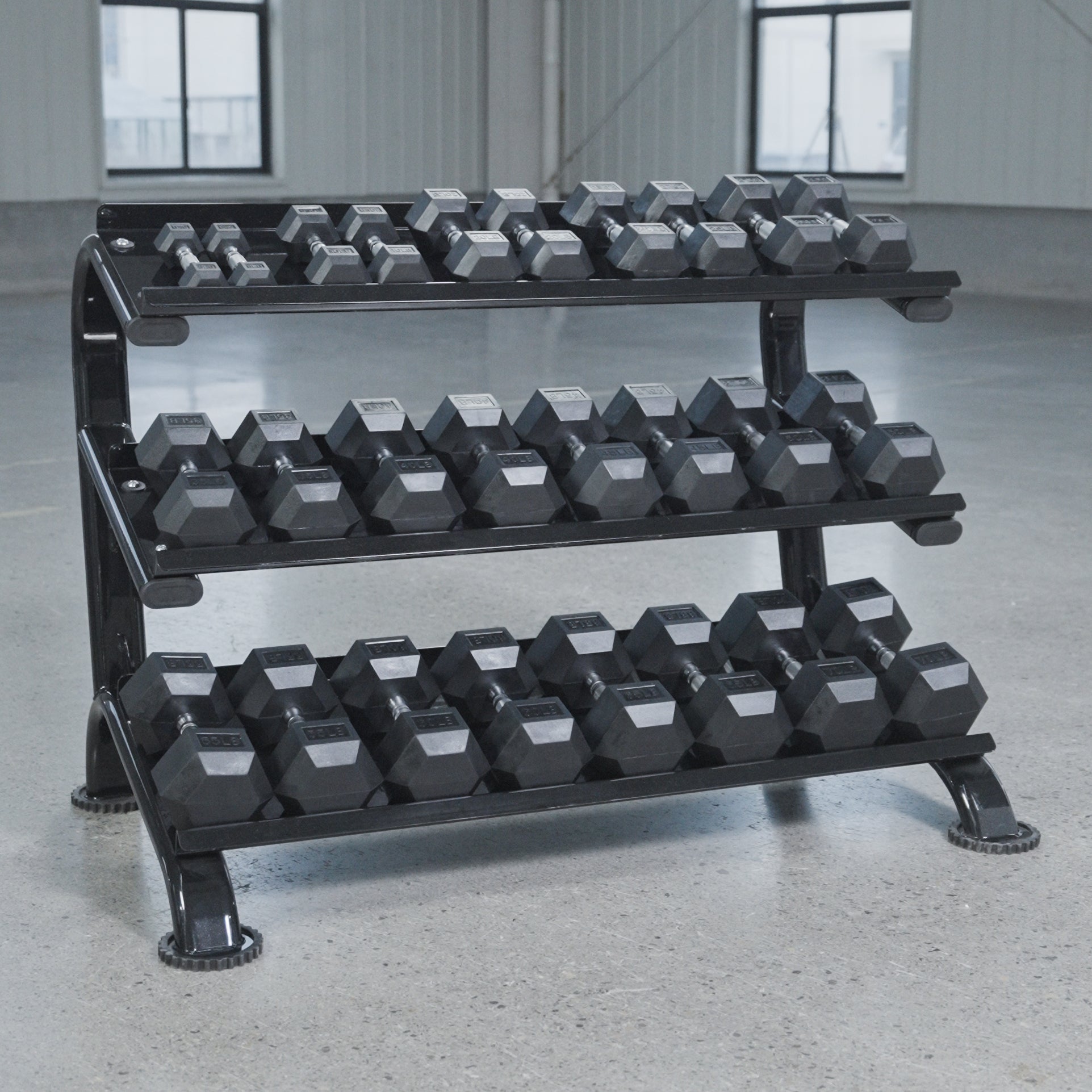 The BefitNow Canada 3 Tier Commercial Hex Dumbbell Rack displays black hex dumbbells on a smooth concrete floor in a spacious, well-lit gym with large windows.