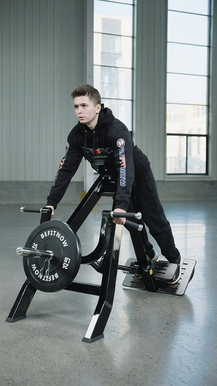 A person in black athletic wear uses the BefitNow Canada AR61 Incline Level Row in a spacious gym with large windows and gray walls, highlighting the versatility of this home gym equipment.