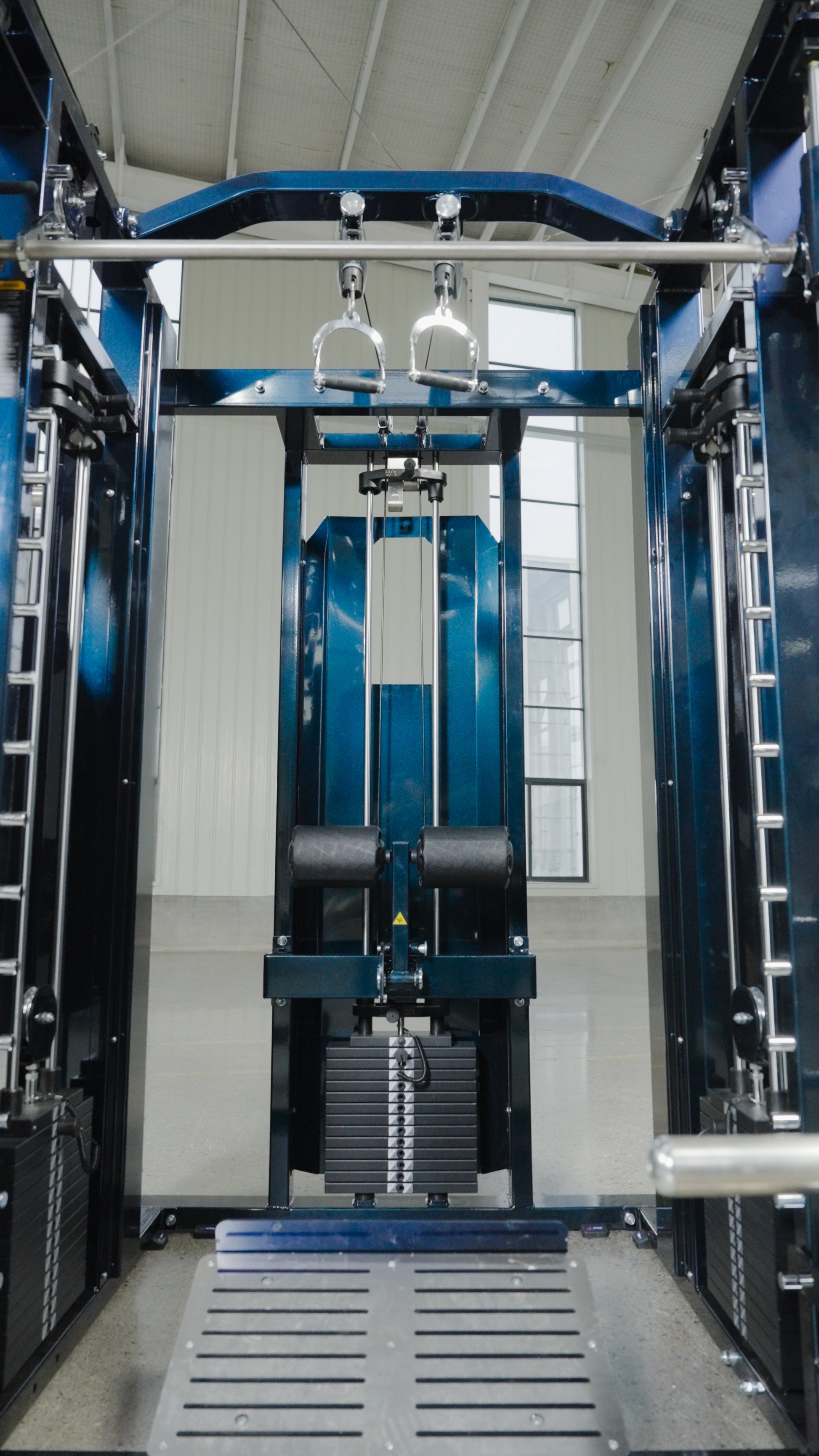 The Professor by BefitNow Canada is a modern all-in-one trainer with adjustable pulleys and weight stacks, showcased in a bright, high-ceilinged gym with large windows.