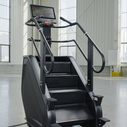 The SkyStep Stair Climber by BefitNow Canada, featuring a black finish and interactive touchscreen, stands in a bright gym with large windows and white walls.
