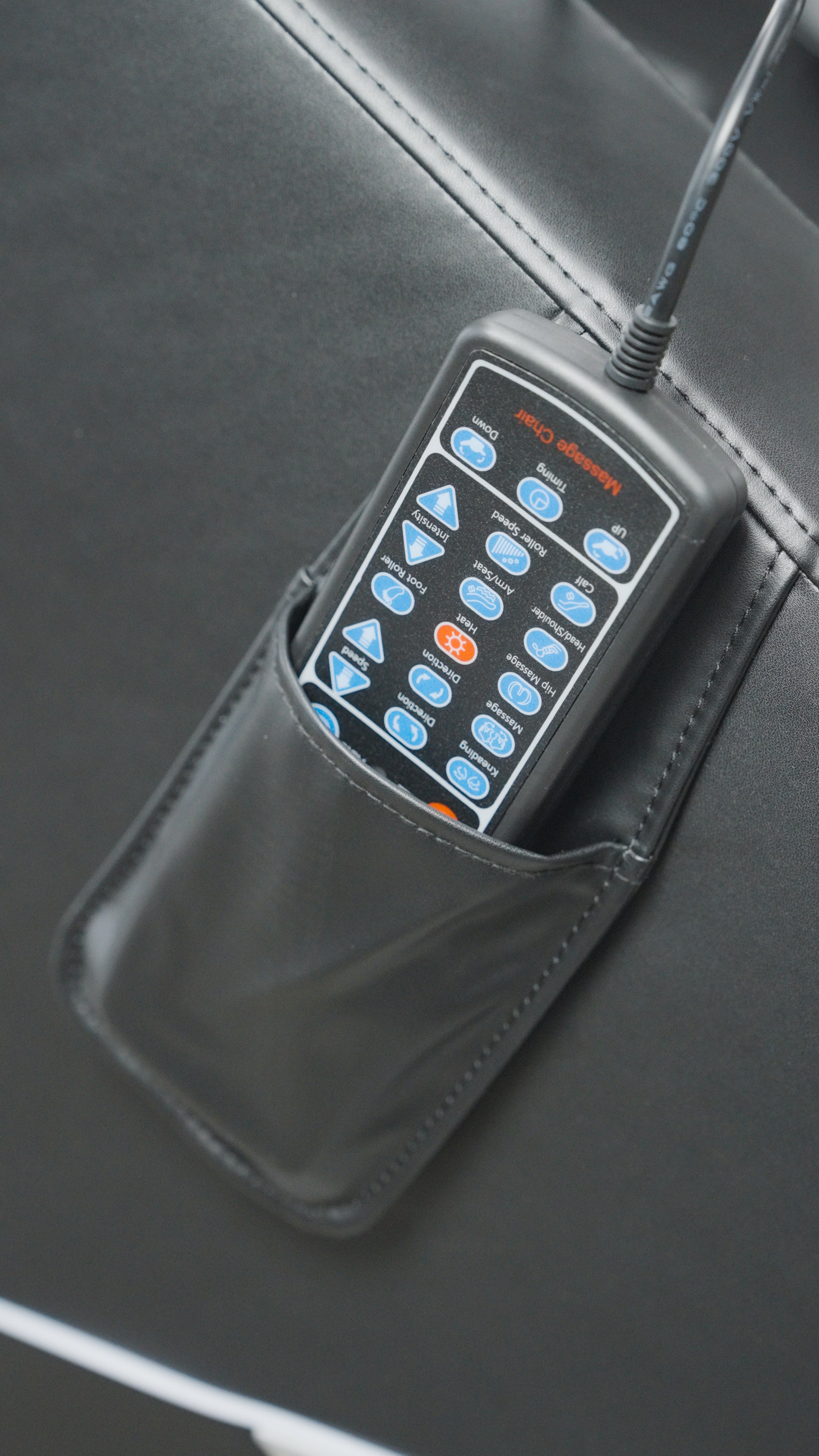 A BefitNow Canada Luxurious Zero Gravity Massage Chair features a black wired remote control with multiple buttons stored in a black leather pouch attached to its side.