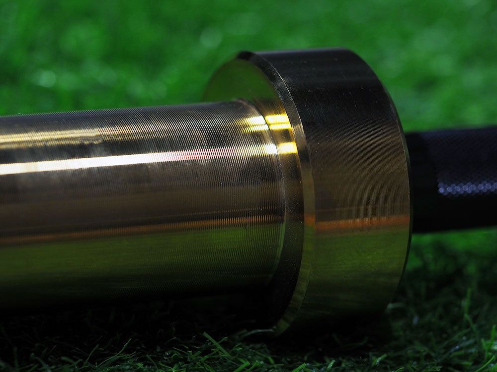 Close-up of a shiny sleeve with a knurled handle from BefitNow Canadas Custom Barbells on grass, reflecting light to highlight its smooth texture and circular shape, exemplifying the barbells quality.
