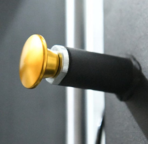 A close-up of a brass door stopper with a rubber buffer mounted on a wall, similar to the design efficiency of the Heavy Duty Smith Machine by BefitNow Canada. The stopper, featuring a gold cap and dark base, prevents doors from damaging walls against a slightly blurred background.
