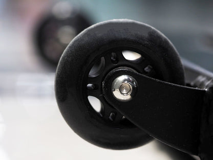 A close-up of a black caster wheel attached to the TM87 Fully Adjustable Commercial Bench by BefitNow Canada shows its metallic structure. Another blurry but shiny wheel appears in the background, both designed for smooth rolling movement.