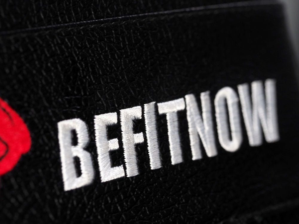 Close-up of BefitNow Canada embroidered in white on black, textured fabric, likely from the TM87 Fully Adjustable Commercial Bench. A small red logo on the left side adds to its sleek design.