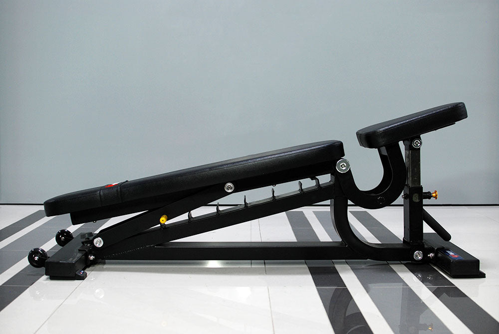 The TM87 Fully Adjustable Commercial Bench by BefitNow Canada, featuring black padding, is set in a decline position on a glossy, striped floor against a neutral wall.